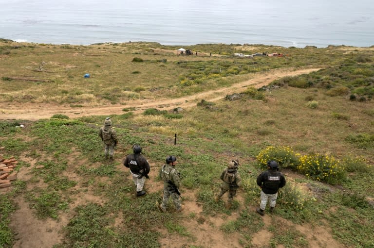 Mexican officers stand guard as rescue and forensics workers as well as prosecutors work at a waterhole where human remains were found near La Bocana Beach, Santo Tomas (Guillermo Arias)