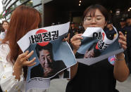 Protesters deface papers showing images of Japanese Prime Minister Shinzo Abe during a rally denouncing Japanese government's decision on their exports to South Korea, in front of the Japanese embassy in Seoul, South Korea, Thursday, July 18, 2019. The signs read: "Abe's government." (AP Photo/Ahn Young-joon)