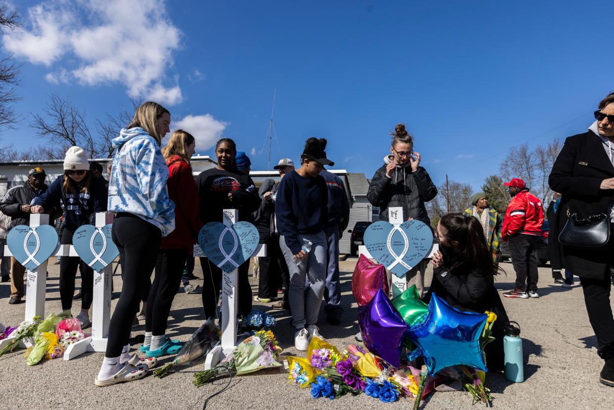 Members of the Rockford East High School softball team sign Jenna Newcomb's memorial cross Thursday, March 28, 2024, during a prayer vigil on Charles Street in Rockford. Several hundred people gathered to honor victims of a mass stabbing the day before.