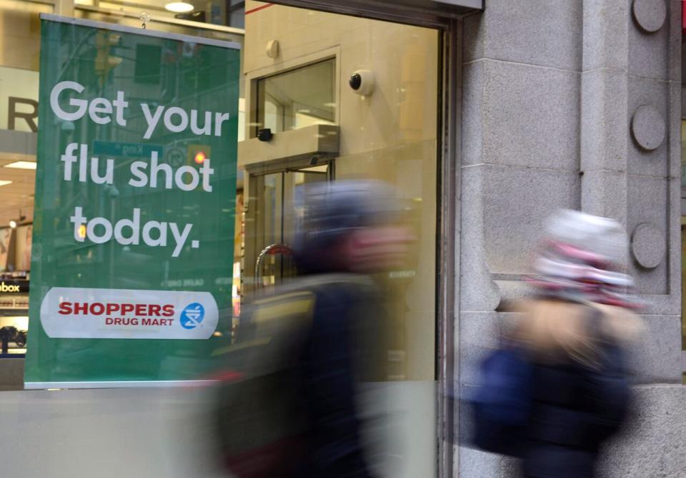 People walk pass a sign for flu shots in Toronto on Tuesday, Jan. 9, 2018. The number of flu cases is continuing to rise across Canada, suggesting the peak of infections with one of the dominant circulating strains could come within a few weeks, or even sooner, say infectious diseases experts, who describe this influenza season as 'unusual.'