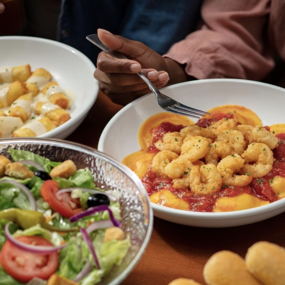 bowl of salad next to a bowl of ravioli topped with shrimp