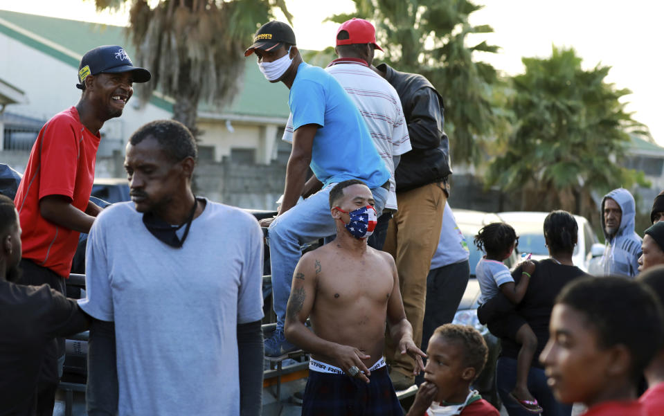 In this May 2, 2020, photo, gang members deliver food in the Manenberg neighborhood of Cape Town, South Africa. A preacher recruited members of street gangs to distribute food to homes and soup kitchens in a violent and poor neighborhood during the coronavirus lockdown. The gang members are observing a truce during the food delivery. (AP Photo/Nardus Engelbrecht)