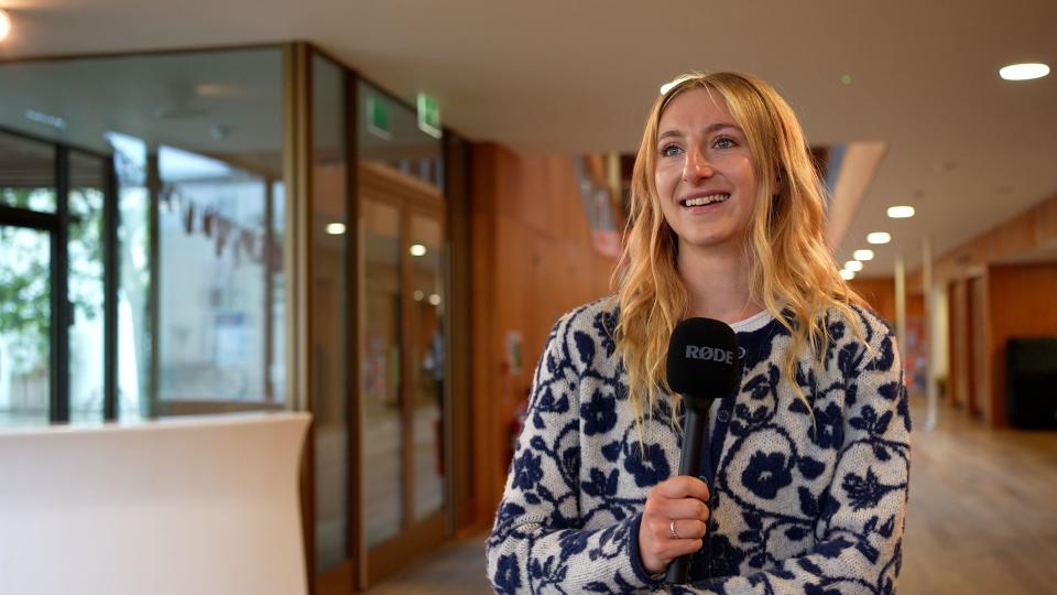 Taylor Swift fan Elspeth Kennedy holding a microphone at a Taylor Swift conference