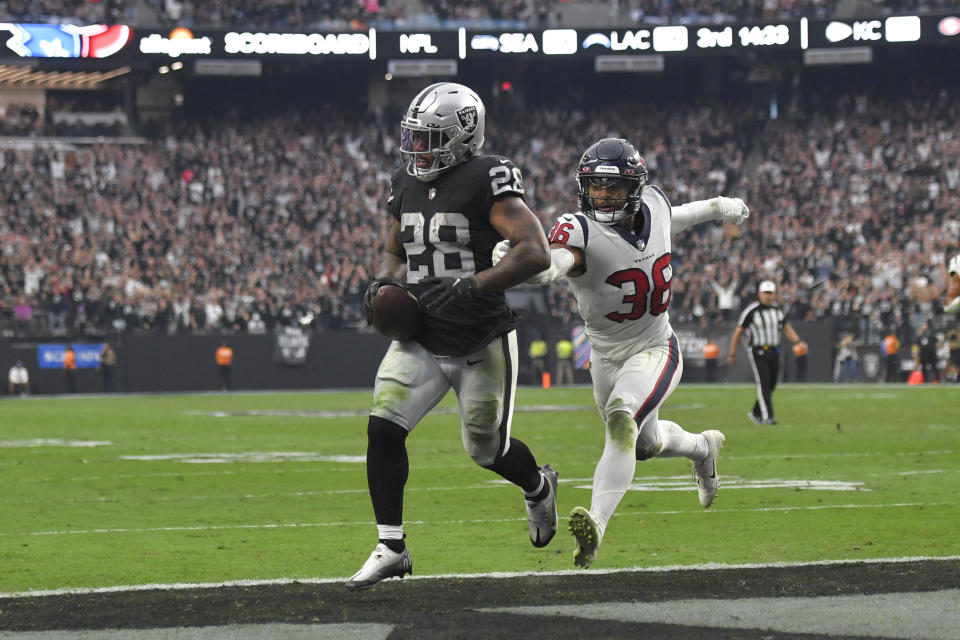 Las Vegas Raiders running back Josh Jacobs, left, scores a touchdown as Houston Texans safety Jonathan Owens defends during the second half of an NFL football game Sunday, Oct. 23, 2022, in Las Vegas. (AP Photo/David Becker)