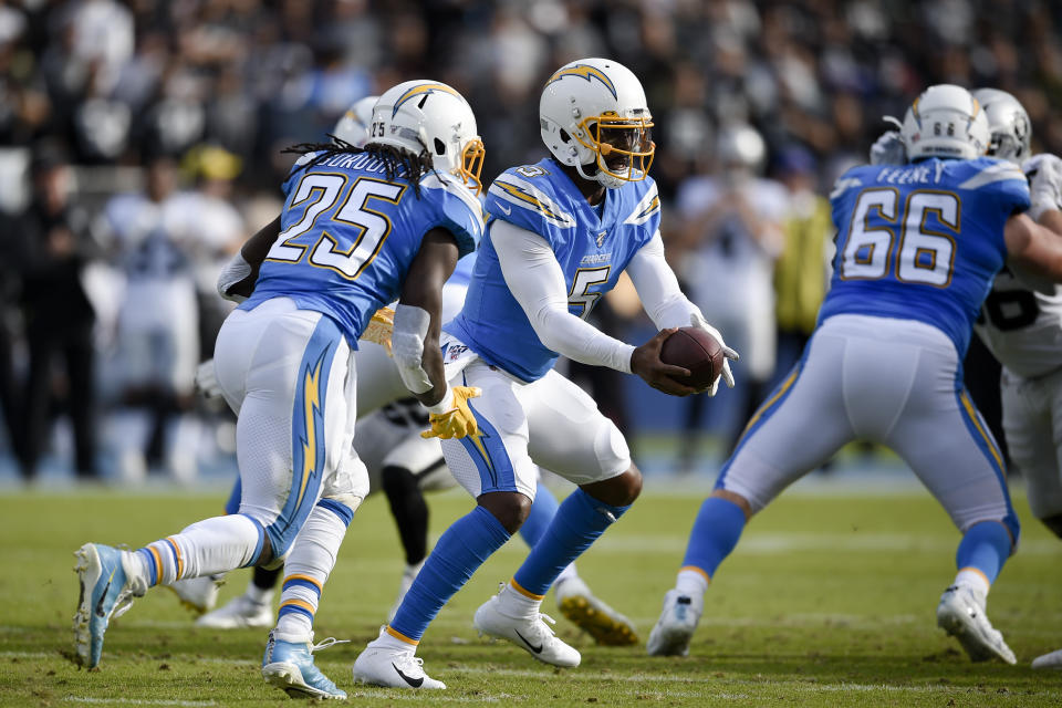 FILE - In this Dec. 22, 2019, file photo, Los Angeles Chargers quarterback Tyrod Taylor, center, prepares to hand off the ball to Melvin Gordon III during the first half of an NFL football game against the Oakland Raiders in Carson, Calif. Taylor has the inside track to be the Chargers' quarterback, but coach Anthony Lynn said the team is still assessing all of their options.(AP Photo/Kelvin Kuo, File)