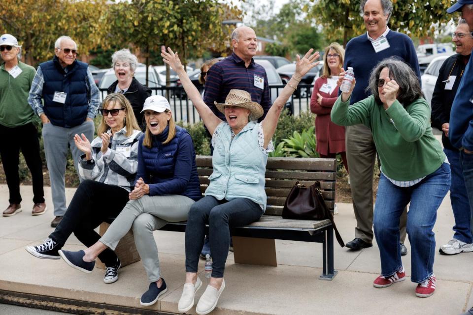 A group of women cheering while sitting on a bench.