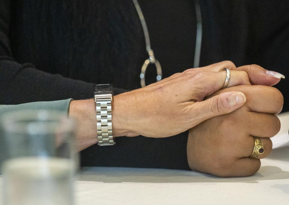 Ellen, left, reaches over and holds Gabby's hand as Gabby begins to cry as she speaks during a press conference