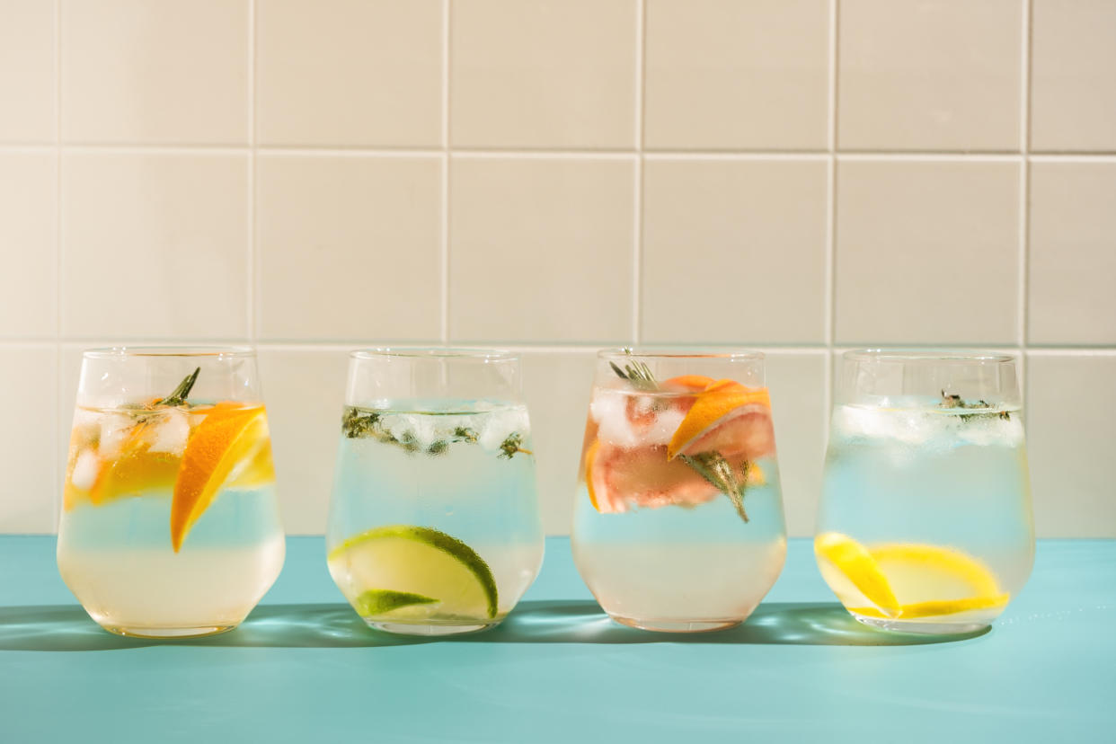 Sommerliches Wasser mit Früchten, Eis und Kräutern in vier Gläsern