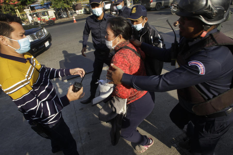 Prum Chenda, center, wife of a jailed former opposition activist, is stopped by security personnel as she tries to reach the Phnom Penh Municipal Court in Phnom Penh, Cambodia, Thursday, Jan. 14, 2021. The trial of more than 60 critics and opponents of the Cambodian government charged with treason and other offenses for taking part in nonviolent political activities resumed Thursday, with rights advocates skeptical that justice is being served. (AP Photo/Heng Sinith)