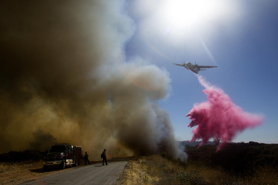 An air tanker drops fire retardant to a brush fire at the Apple Fire in Cherry Valley, Calif., Saturday, Aug. 1, 2020. A wildfire northwest of Palm Springs flared up Saturday afternoon, prompting authorities to issue new evacuation orders as firefighters fought the blaze in triple-degree heat.(AP Photo/Ringo H.W. Chiu)