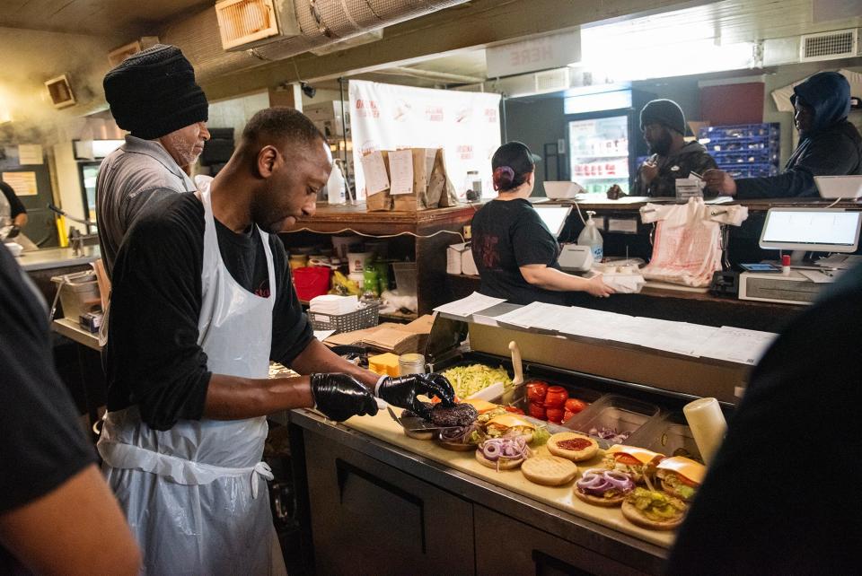 Cordell Spann, prep and grill cook, places a patty onto a bun at Stamps Super Burgers in Jackson, Miss., on Friday, Jan. 5, 2024.