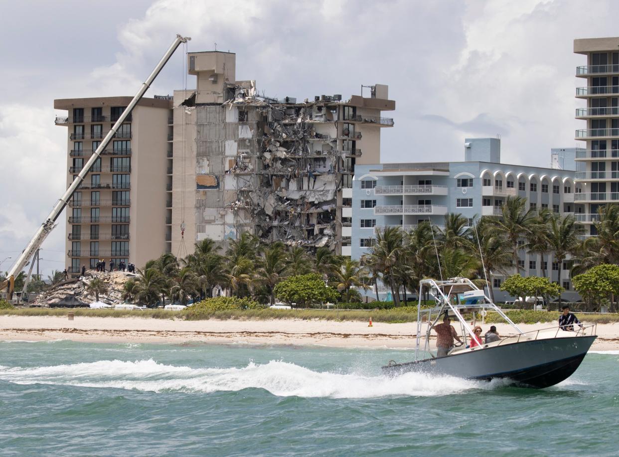 Un bote pasa frente a la costa mientras los miembros del equipo de Búsqueda y Rescate Urbano del Sur de Florida buscan posibles sobrevivientes en el edificio de condominios Champlain Towers South de 12 pisos parcialmente derrumbado (Getty)