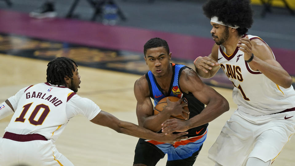 Oklahoma City Thunder's Theo Maledon, center, drives between Cleveland Cavaliers' Darius Garland, left, and Jarrett Allen in the second half of an NBA basketball game, Sunday, Feb. 21, 2021, in Cleveland. (AP Photo/Tony Dejak)