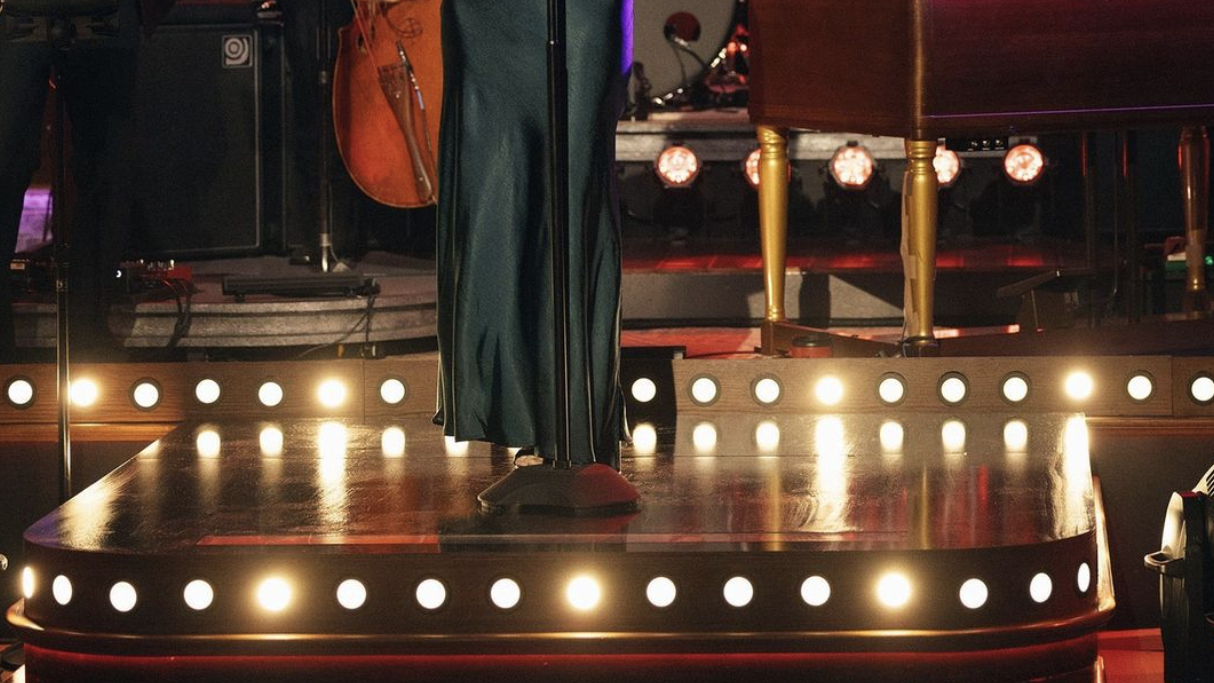kelly clarkson singing on a stage in a dark green satin maxi dress