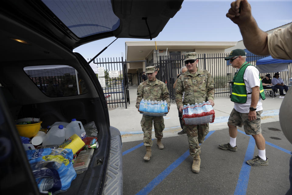 Members of the National Guard load water onto an SUV in the aftermath of an earthquake Sunday, July 7, 2019, outside Trona High School in Trona, Calif. (AP Photo/Marcio Jose Sanchez)