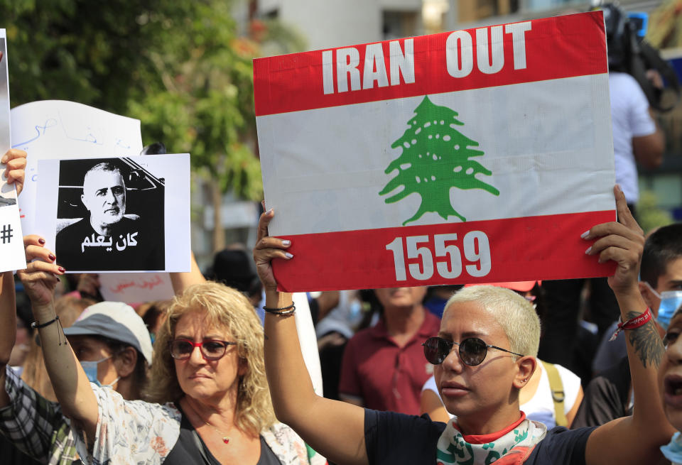 A protester holds a portrait Wafiq Safa, a top Hezbollah security official, with Arabic that reads: "He knew," during a demonstration of solidarity with Judge Tarek Bitar who is investigating last year's deadly seaport blast, in Beirut, Lebanon, Wednesday, Sept. 29, 2021. Hundreds of Lebanese, including families of the Beirut port explosion victims, rallied Wednesday outside the court of justice in support of Bitar after he was forced to suspend his work. Bitar is the second judge to take on the complicated investigation. (AP Photo/Hussein Malla)