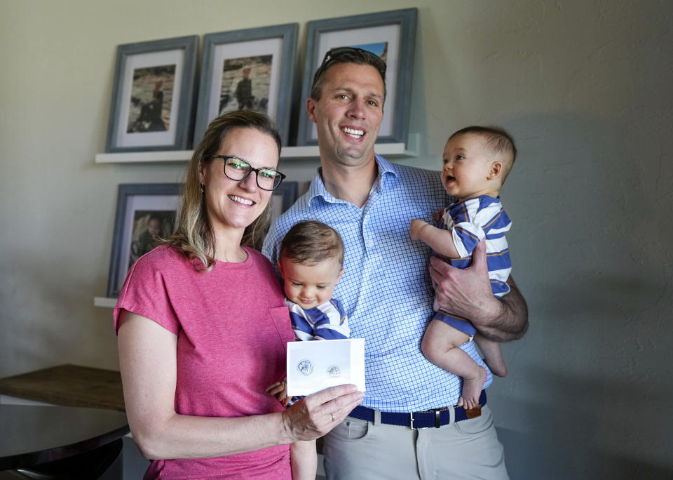 Amanda and Ryan Visser hold their embryo-adopted six-month-old sons Collin and Jackson while showing a photo of the fertilized embryos at their home, Monday, May 13, 2024, in Sterling, Colorado. When faced with infertility, Christians who believe life begins at or around conception wrestle with the ethics of IVF and how to build a family in a way that conforms with their beliefs. (AP Photo/Jack Dempsey)