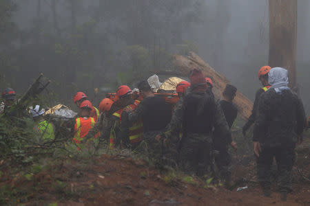 Rescue workers carry two bodies found in the area where Hilda Hernandez, the sister of Honduran President Juan Orlando Hernandez, and five others died when the helicopter they were traveling in crashed in San Matias, Honduras, December 17, 2017. REUTERS/ Jorge Cabrera