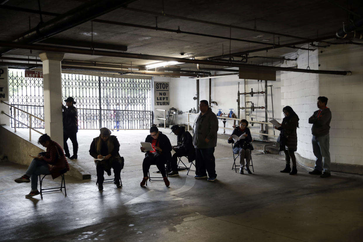 In this March 13, 2020, file photo, unionized hospitality workers wait in line in a basement garage to apply for unemployment benefits at the Hospitality Training Academy in Los Angeles. (Credit:Marcio Jose Sanchez, AP Photo)