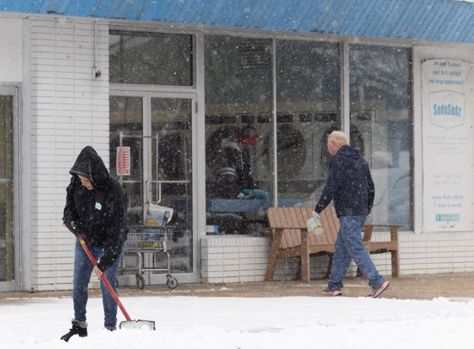 An employee shovels snow on the sidewalk outside the Soda Sudz Laundry in Lakehurst.