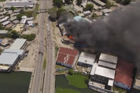 In this image made from aerial video, smoke rises from burning buildings during a protest in the capital of Honiara, Solomon Islands, Thursday, Nov. 25, 2021. Prime Minister Manasseh Sogavare declared a lockdown after about 1,000 people took to the streets in the capital for a second day, demanding his resignation over a host of domestic issues, according to local media reports. (Australian Broadcasting Corporation via AP)