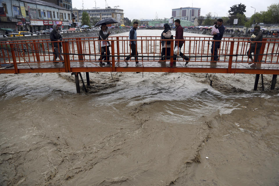 Afghans walk across a bridge as heavy rain falls in Kabul, Afghanistan, Tuesday, April 16, 2019. Afghan officials say at least five more people have been killed and 17 are missing as a new wave of heavy rains and flooding swept across the country's western Herat province. (AP Photo/Rahmat Gul)