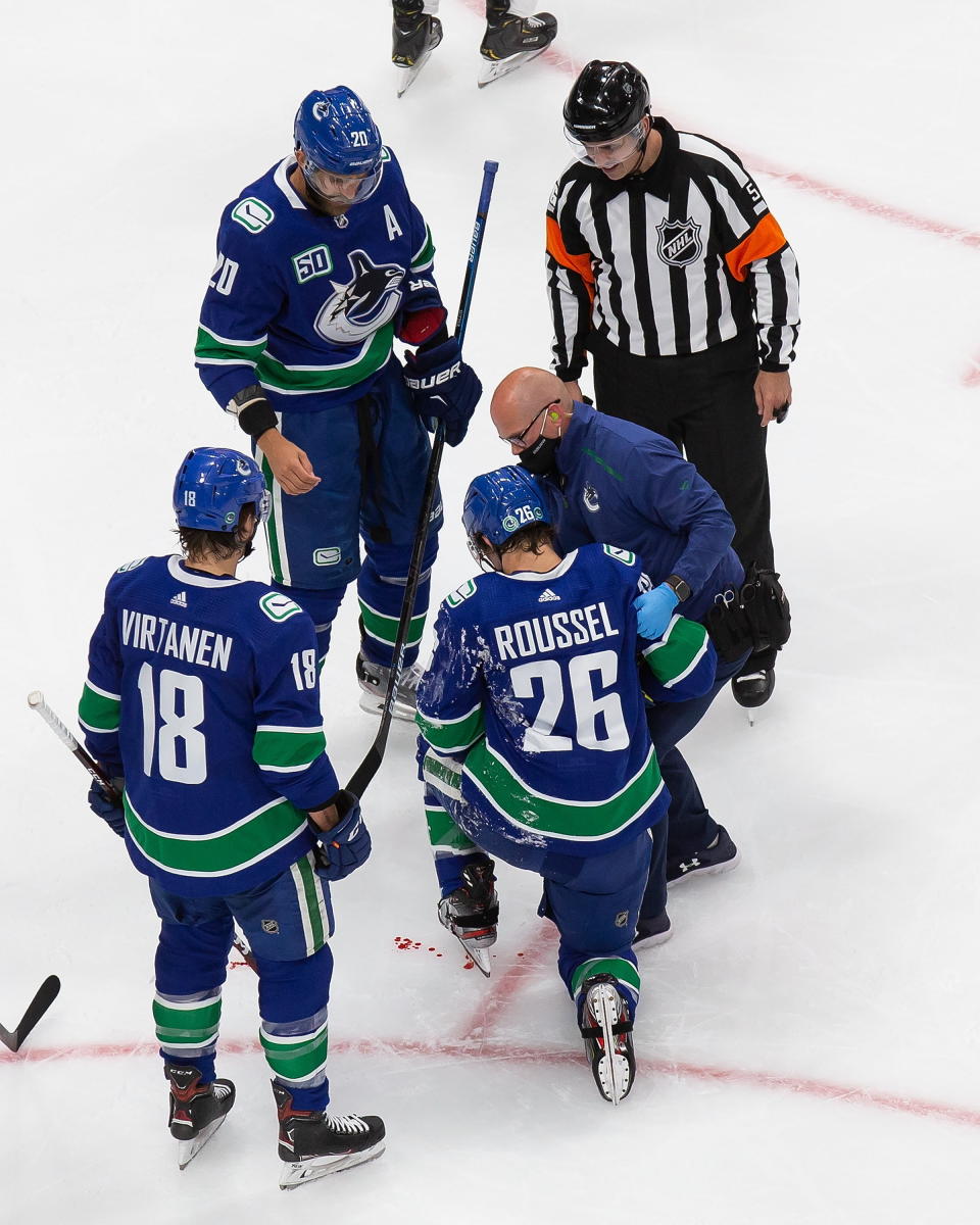 Vancouver Canucks' Antoine Roussel (26) is helped off the ice by a trainer during the third period of the team's NHL hockey playoff game against the Minnesota Wild in Edmonton, Alberta, Tuesday, Aug. 4, 2020. (Codie McLachlan/The Canadian Press via AP)