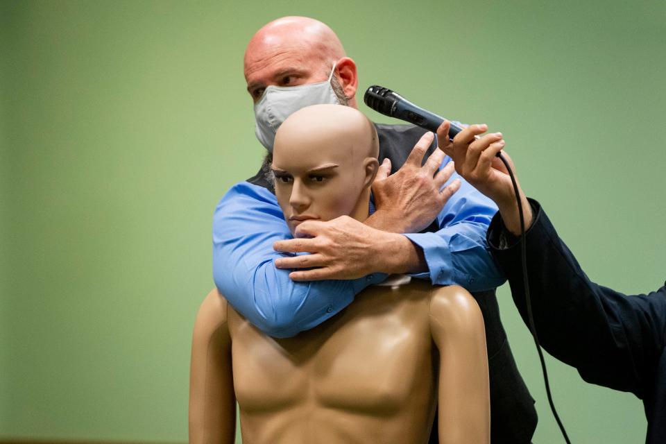 Retired police officer Shane Brisco demonstrates that an officer's elbow should be aligned with the restrained person's chin to properly complete a vascular neck restraint during the Christopher Smelser trial at the 3rd District Court on Wednesday, July 13, 2022.