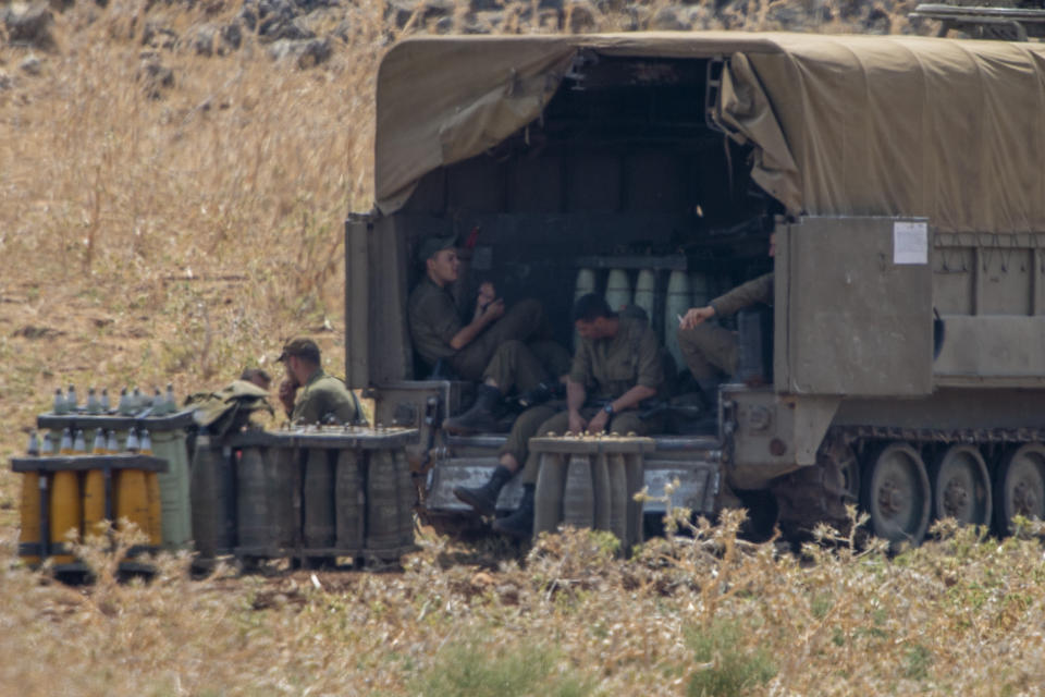 Israeli soldiers sit by shells next to an Israeli mobile artillery unit placed in northern Israel near the border with Lebanon, Tuesday, July 28, 2020. Israeli forces have exchanged fire with Hezbollah militants along the volatile Israeli-Lebanese frontier. (AP Photo/Ariel Schalit)