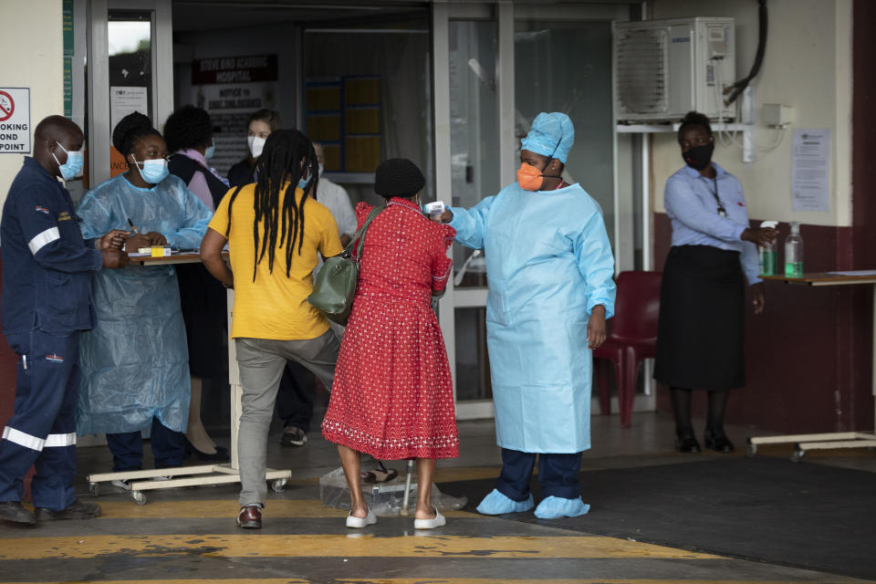 A health worker checks the temperature of an elderly patient at the emergency entrance of the Steve Biko Academic Hospital in Pretoria, South Africa, Monday, Jan. 11, 2021, which is battling an ever-increasing number of COVID-19 patients. (AP Photo/Themba Hadebe)