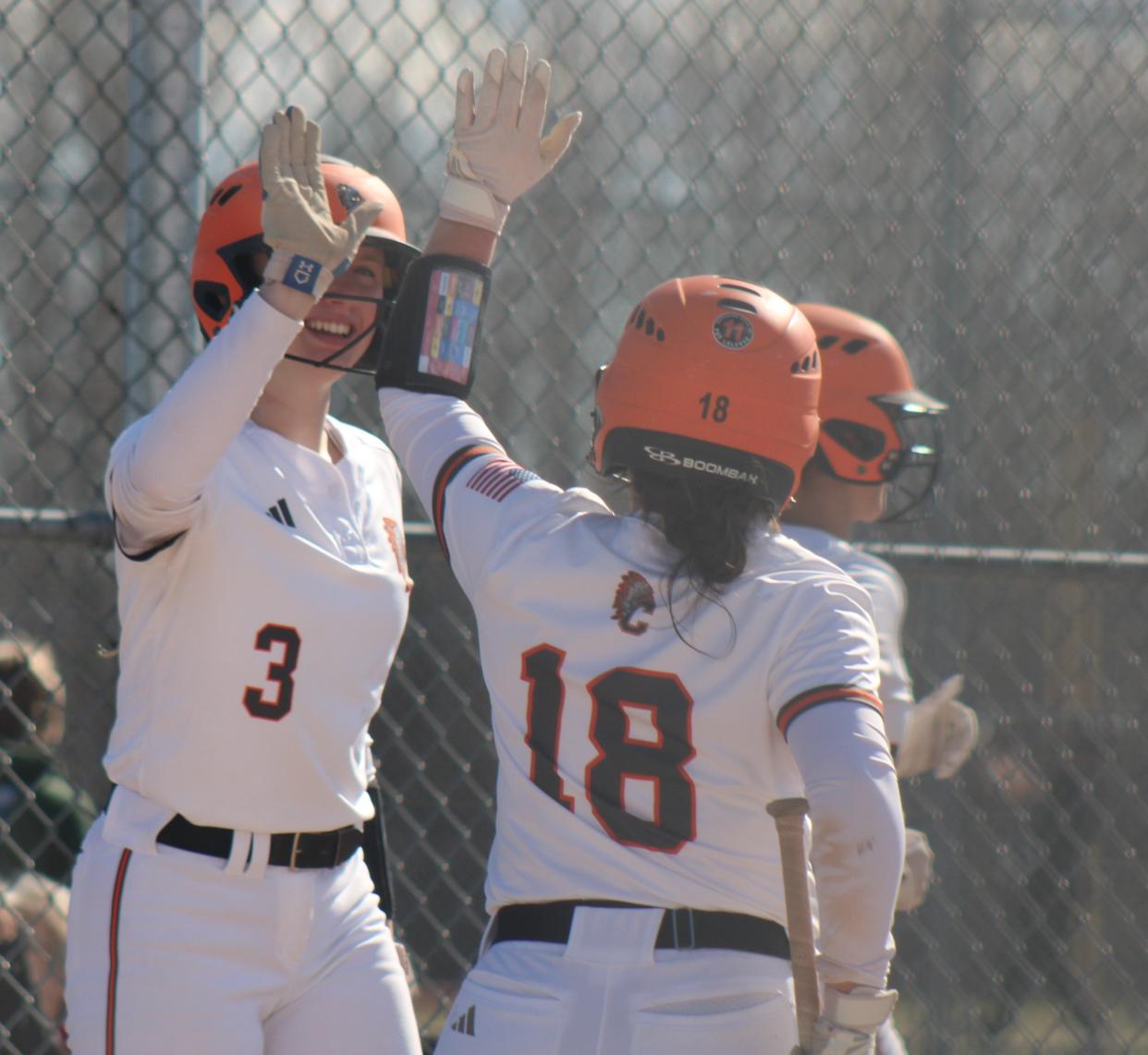 Cheboygan junior Tessa Lake (3) high-fives sophomore teammate Presley Chamberlain (18) after Chamberlain scored to give Cheboygan a lead in game one of a softball home doubleheader against Traverse City West.