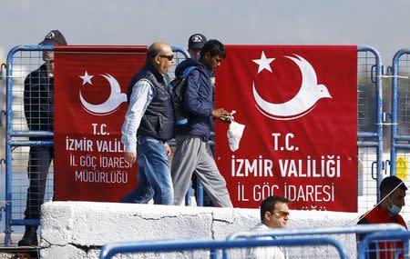 A migrant is escorted by a Turkish police officer as he arrives in the Turkish coastal town of Dikili, Turkey, April 4, 2016. REUTERS/Murad Sezer