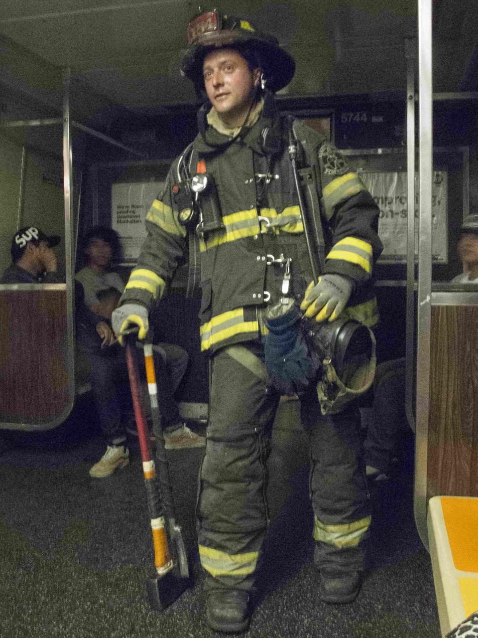 A firefighter stands next to passengers inside the "F" train after it derailed in the Woodside neighborhood located in the Queens borough of New York May 2, 2014. (REUTERS/Connie Wang)