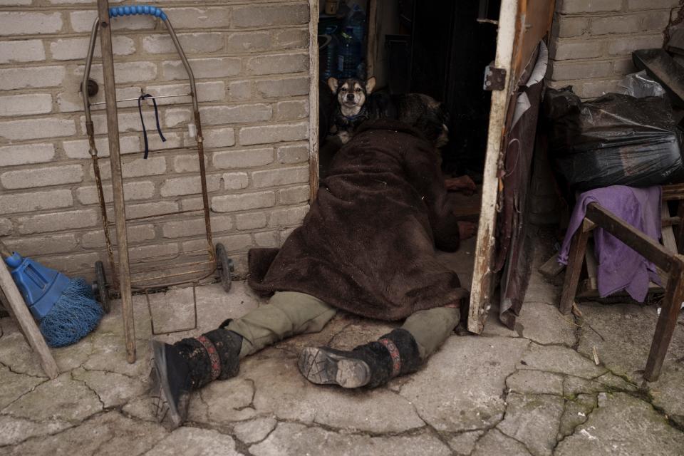 A dog stands next to the body of an elderly woman killed at the entrance of her house in Bucha (Copyright 2022 The Associated Press. All rights reserved.)