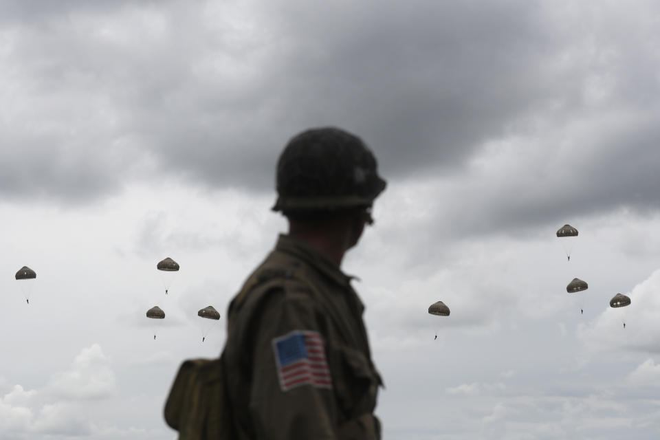 A WWII enthusiasts watches French and British parachutists jumping during a commemorative parachute jump over Sannerville, Normandy, Wednesday, June 5, 2019. Extensive commemorations are being held in the U.K. and France to honor the nearly 160,000 troops from Britain, the United States, Canada and other nations who landed in Normandy on June 6, 1944 in history's biggest amphibious invasion. (AP Photo/Thibault Camus)