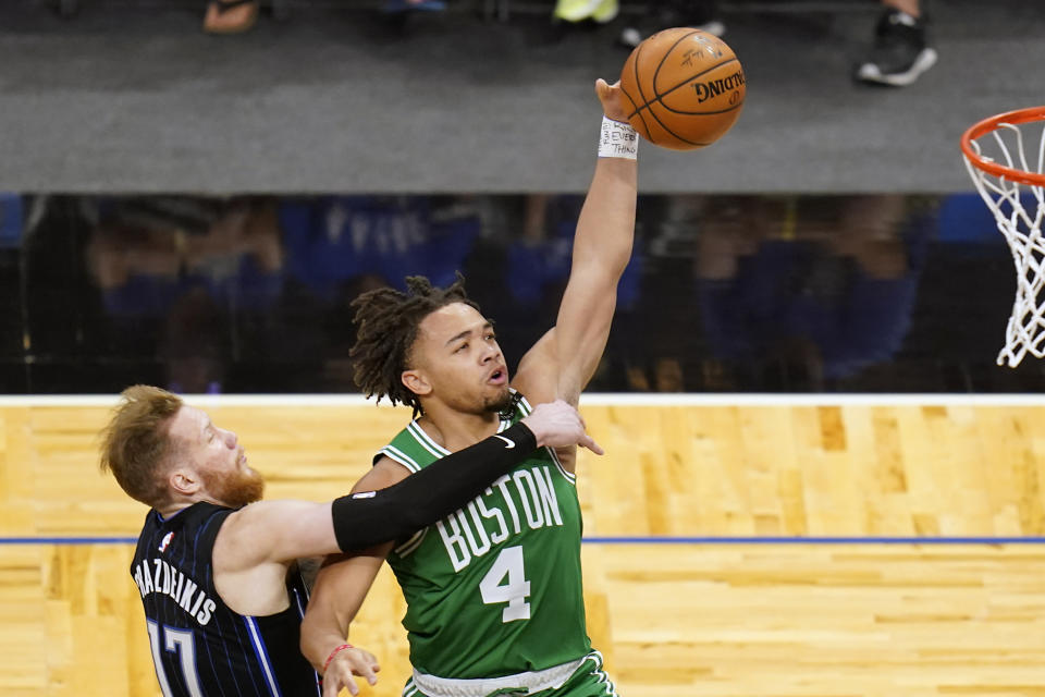 Orlando Magic forward Ignas Brazdeikis, left, fouls Boston Celtics guard Carsen Edwards (4) as he goes up for a shot during the second half of an NBA basketball game, Wednesday, May 5, 2021, in Orlando, Fla. (AP Photo/John Raoux)