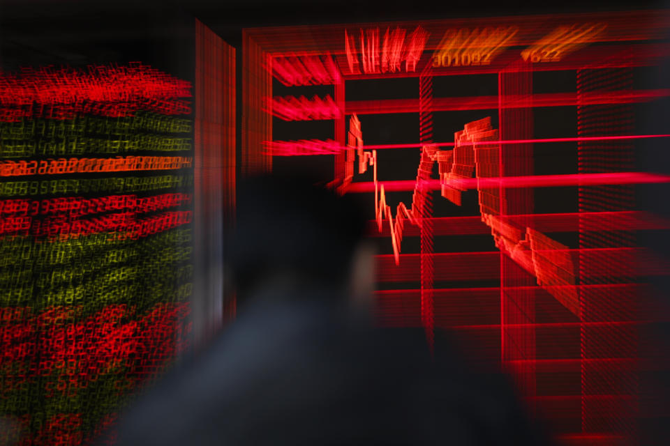 In this Thursday, Dec. 19, 2019, photo, Chinese investor monitors stock prices in front of an electronic screen displaying Shanghai Composite Index at a brokerage house in Beijing. Stocks were mixed in early trading in Asia on Friday, Dec. 20, 2019, after Wall Street posted more record highs, extending the market's gains for the week. (AP Photo/Andy Wong)