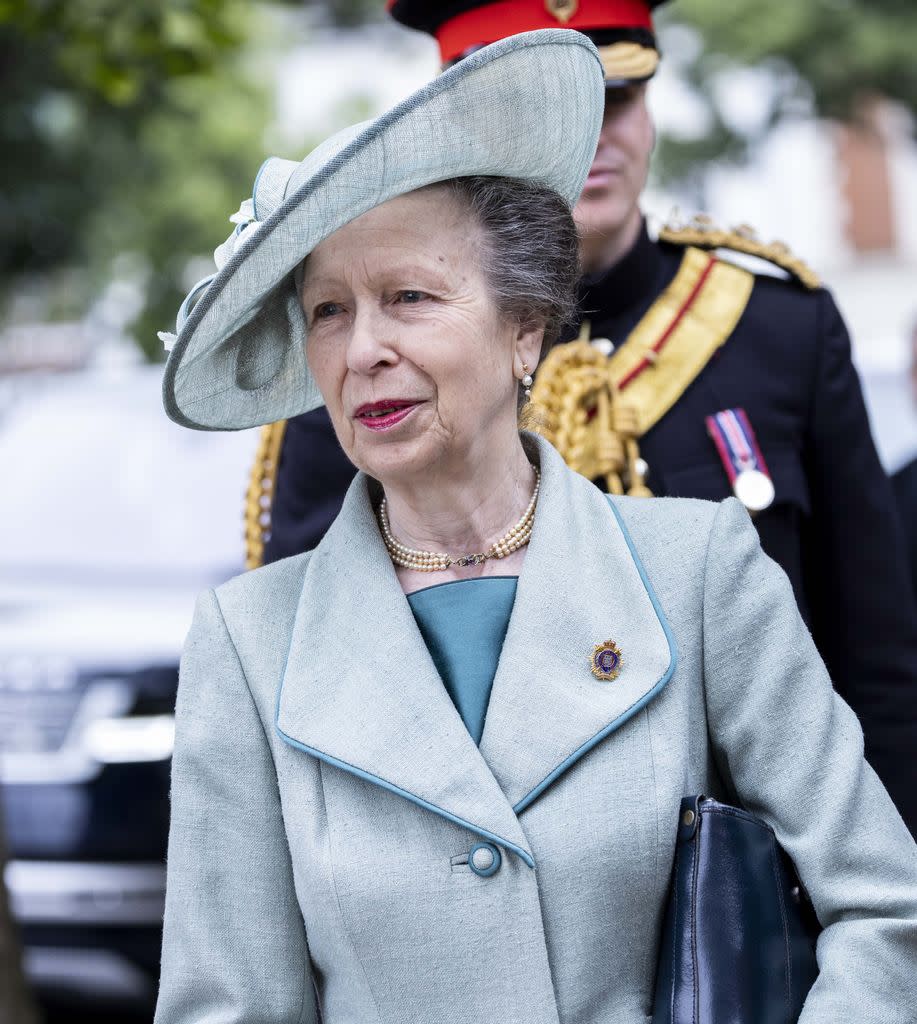 Princess Anne wearing blue hat and matching coat with pearl necklace