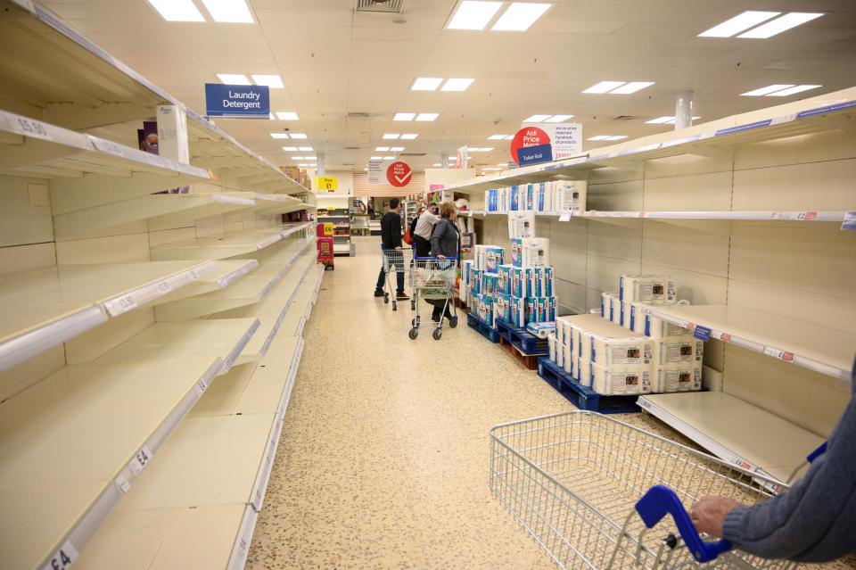 Shoppers peruse near-empty toilet roll shelves at a  supermarket in the centre of York, northern England, on March 19, 2020. - Britain's supermarkets on Wednesday stepped up efforts to safeguard supplies, especially for vulnerable and elderly customers, as the sector battles stockpiling caused by coronavirus panic. (Photo by Oli SCARFF / AFP) (Photo by OLI SCARFF/AFP via Getty Images)