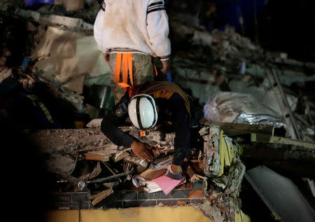 A rescue worker pulls binders from the rubble of a collapsed multi family residential after an earthquake in Mexico City, Mexico September 21, 2017. REUTERS/Daniel Becerril