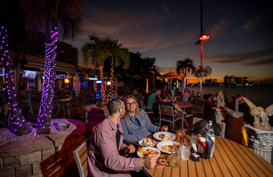 Ignacio Seijo, left, and Andrea liguori enjoy a meal at Shuckers Waterfront Bar & Grill on Tuesday, Nov. 15, 2022, in North Bay Village, Fla.