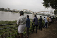 People gather by the Periyar River as they anticipate water levels to rise following opening of gates of the Idukki dam in Kochi, Kerala state, Tuesday, Oct.19, 2021. Several dams in the state are nearing their full capacity and expecting more rains in the coming days, authorities released water as a precautionary measure. (AP Photo/R S Iyer)