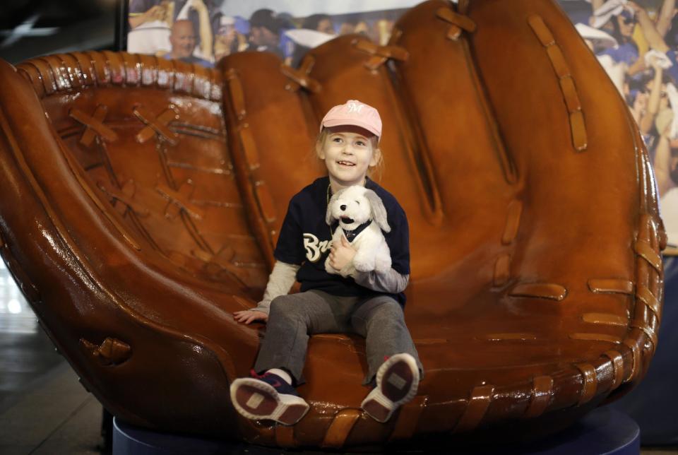 Molly Andersen, of Darien, Wis., sits in a glove before the opening day baseball game between the Milwaukee Brewers and Atlanta Braves at Miller Park, Monday, March 31, 2014, in Milwaukee. (AP Photo/Jeffrey Phelps)