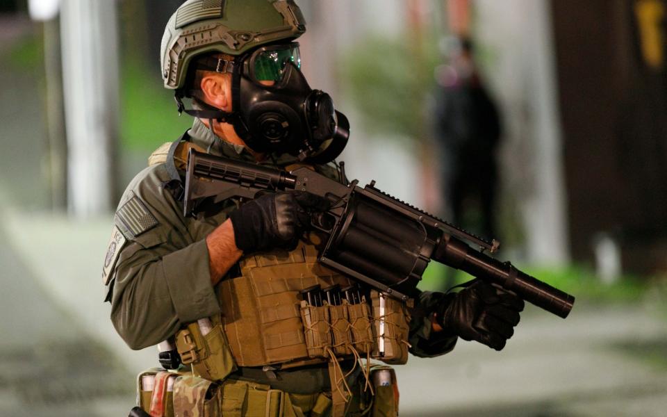 A Special Response Team operator holds a less-lethal rifle during protest