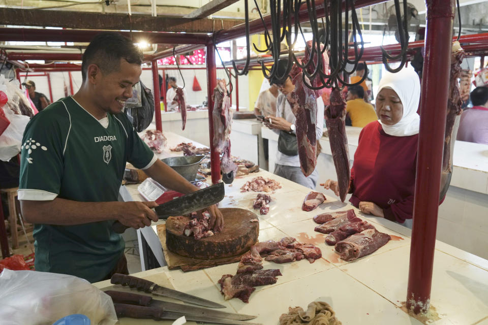 FILE - A butcher serves a customer at a market in Jakarta, Indonesia, Wednesday, March 22, 2023, during preparations to welcome the holy month of Ramadan, expected to start the following day. (AP Photo/ Ahmad Ibrahim, File)