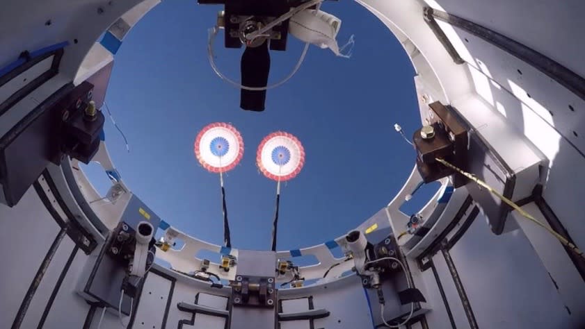     View of parachutes being deployed over a spaceship. 