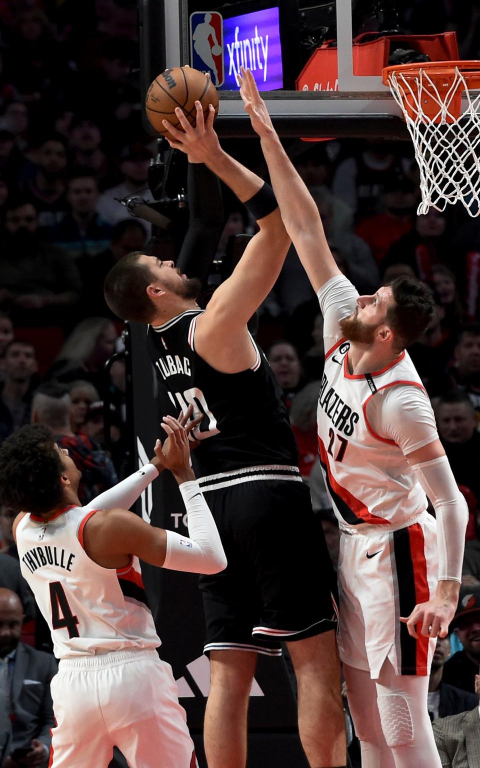 Los Angeles Clippers center Ivica Zubac (center) shoots from between Portland Trail Blazers center Jusuf Nurkic (right) and guard Matisse Thybulle (left) during the first half of an NBA basketball game in Portland on March 19, 2023.