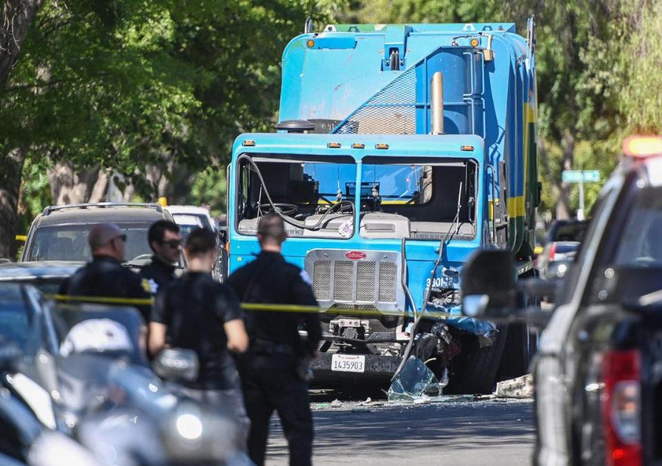 Fresno police investigate a scene at Chestnut and Lane avenues where a white vehicle, traveling at a high rate of speed, hit a garbage truck and then ended up in the yard of a residence on Thursday, Aug. 11, 2022. The driver of the white car was pronounced dead at the scene.