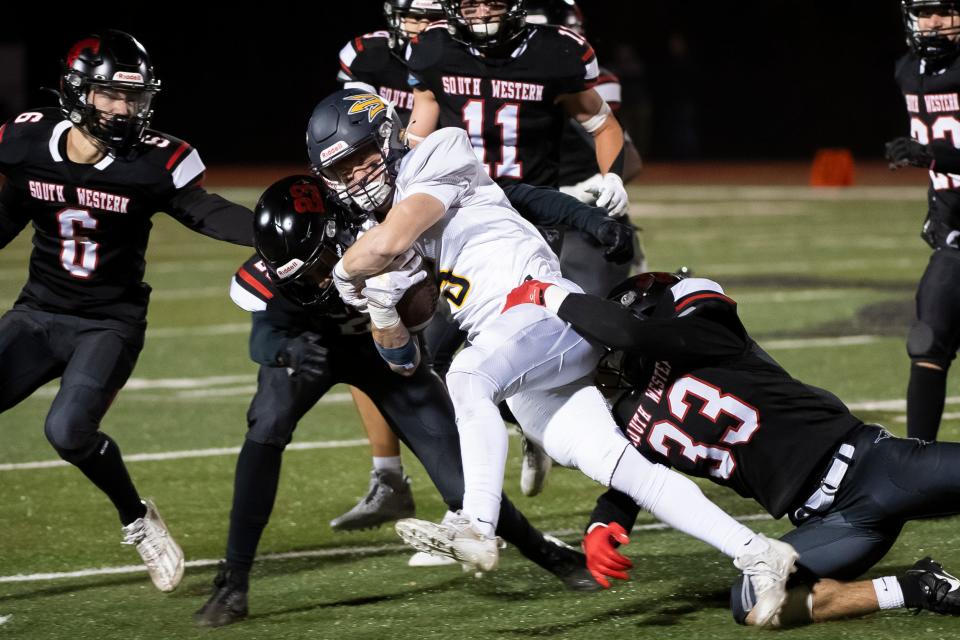 South Western's Alek Newman (23) and Logan Klinedinst (33) combine for a tackle on Greencastle-Antrim running back Carter Coons (5) during a District 3 Class 5A first round football game Nov. 3, 2023, in Penn Township. The Mustangs won, 21-3.