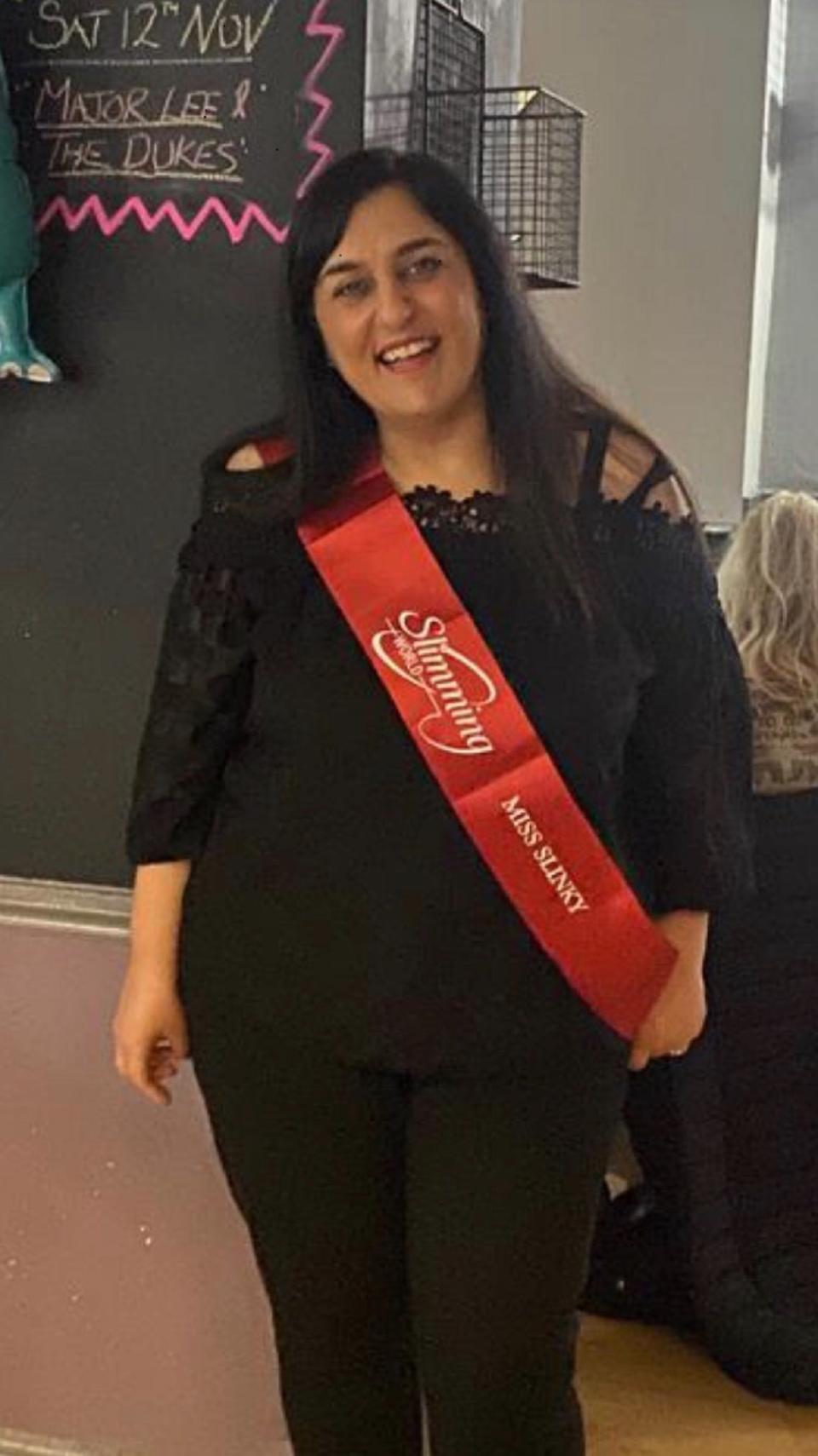 Flora White smiling at the camera wearing a sash 